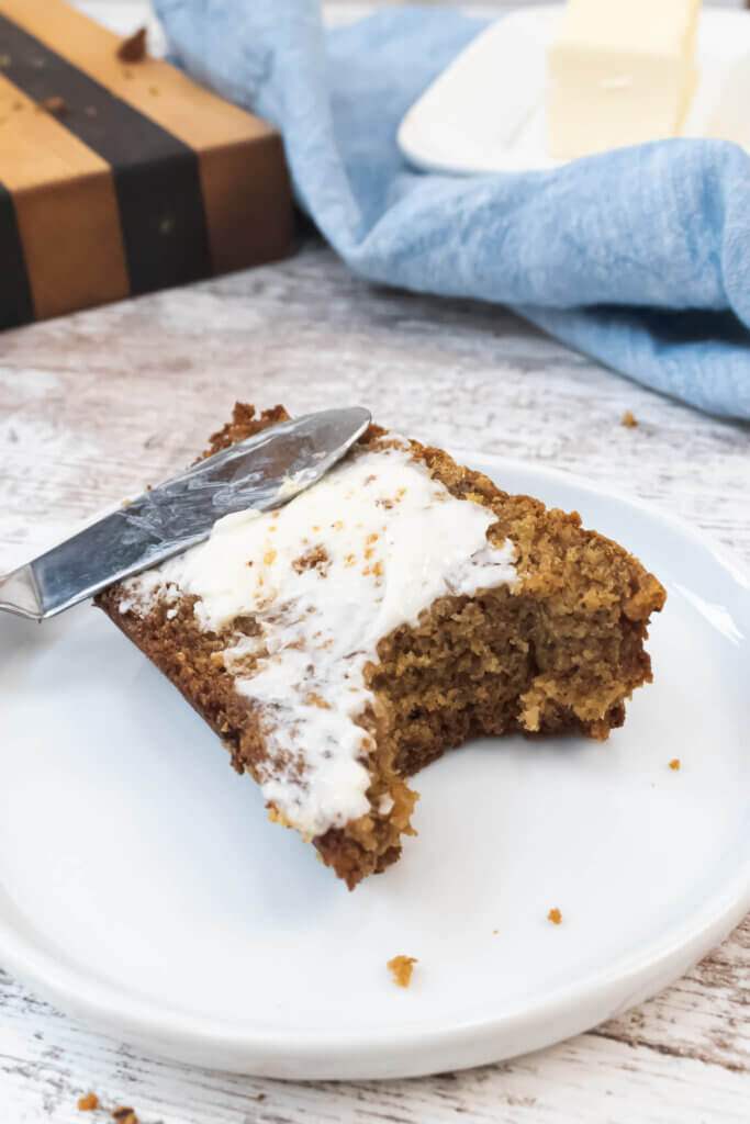 banana bread covered in butter smear on a white plate