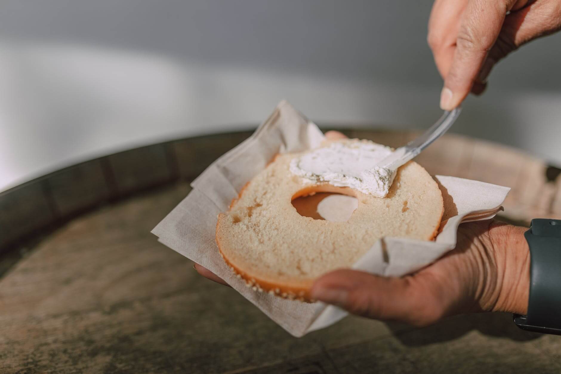 person spreading cream cheese on a bagel for pre workout, during, and post workout nutrition